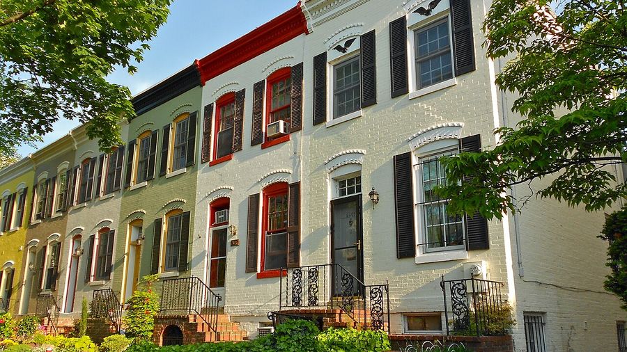 Painted brick rowhouse facades with black shutters on a Washington, DC block
