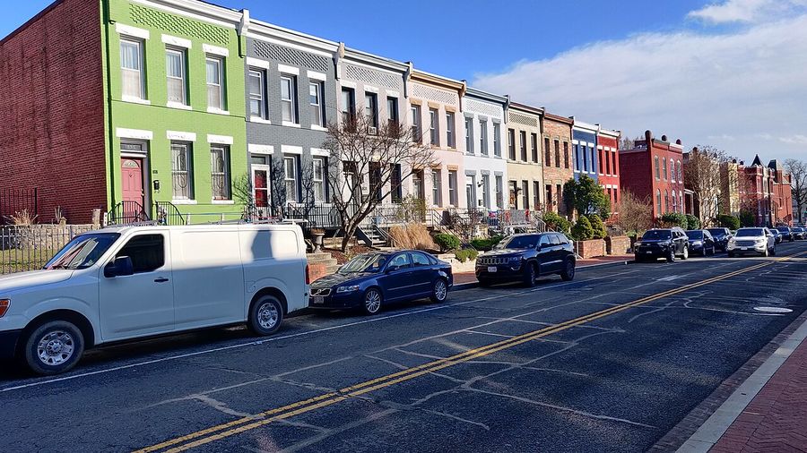 Long row of colourful rowhouses along a sunny Washington, DC street