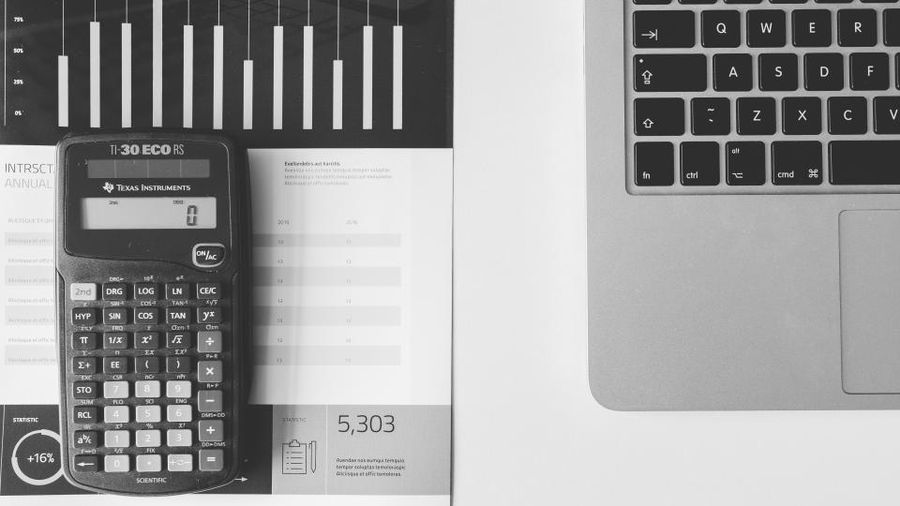 Calculator on printed figures beside a laptop keyboard