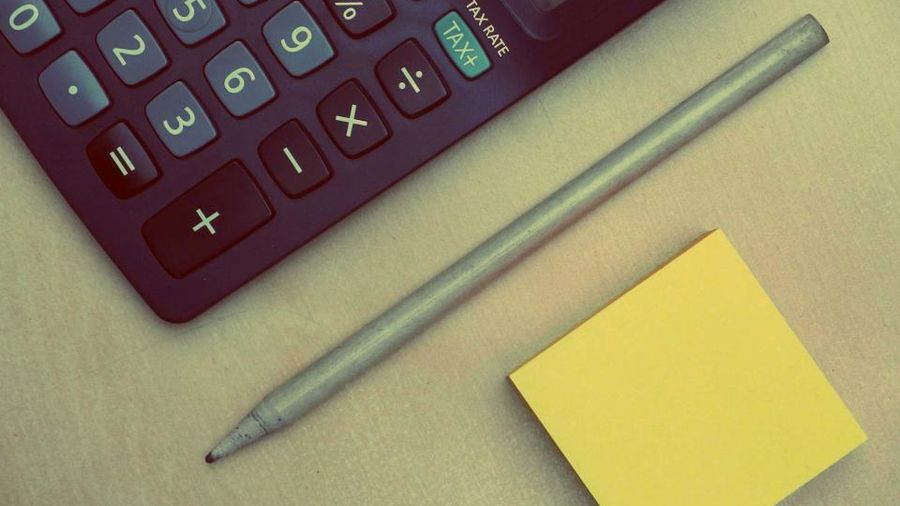 Calculator, pencil and sticky note on a desk, ready to run rental numbers