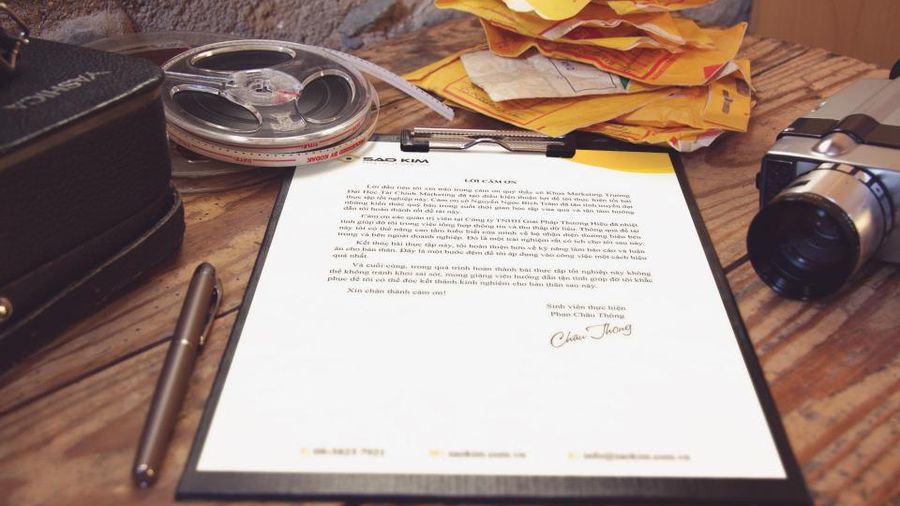 Signed letter on a clipboard surrounded by envelopes and office items
