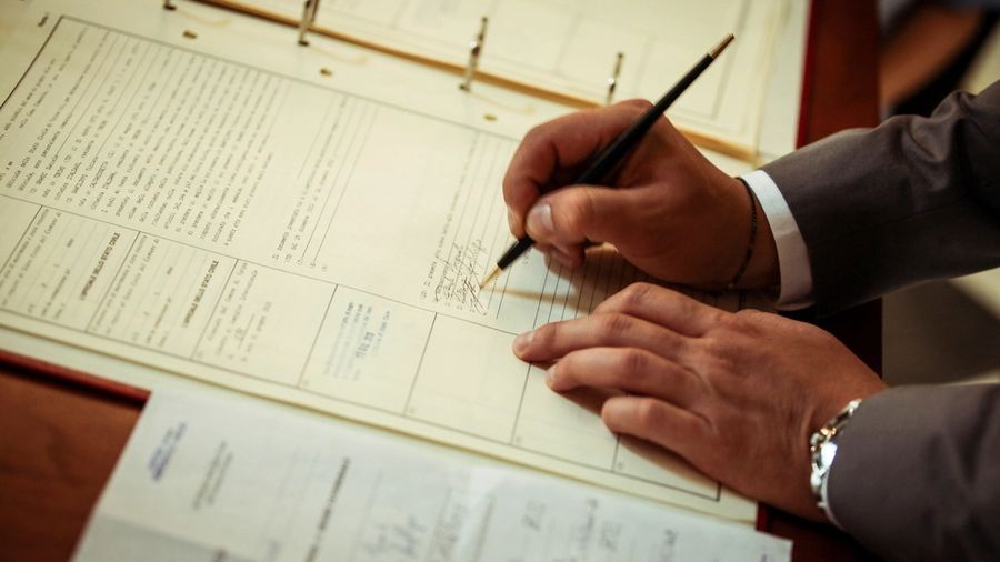 Investor in a suit signing loan documents at a desk