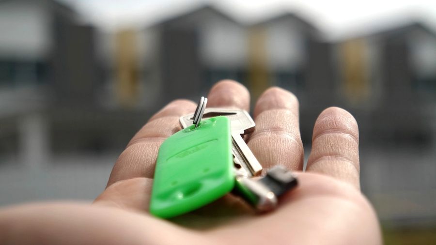 Open hand holding a set of house keys in front of a row of homes
