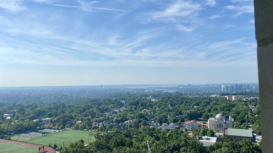 Aerial view over tree-lined Washington, DC neighborhoods toward the skyline